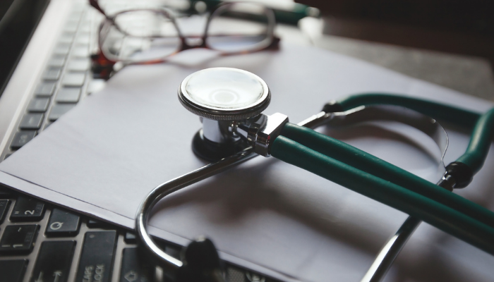 A doctor in a white coat consulting with a patient via video call.